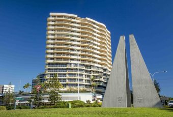 High-Rise Apartment Building Behind Nsw–qld Border Monument Under Clear Blue Sky In Tweed Heads — Metwide Communications in Tweed Heads, QLD
